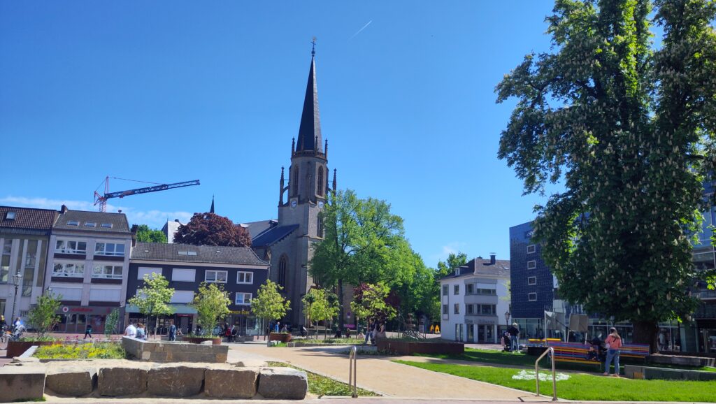 Der Berliner Platz – lebendiges Herz der Gütersloher Innenstadt, eingerahmt von Cafés, Geschäften und der Martin-Luther-Kirche.