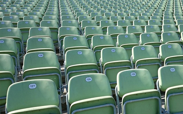 Viele Klappsitze mit Nummerierungen. Vermutlich die Ansicht eines Stadions.
