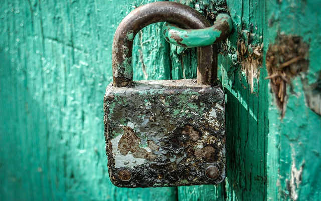 Rostiges Vorhängeschloss an einer grünen Holztür – Symbol für sicheres Webdesign, Datenschutz und verantwortungsvollen Umgang mit Passwörtern.